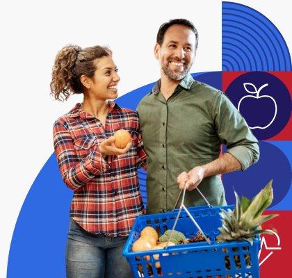 A smiling couple holding their basket full of groceries. 