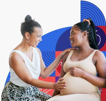 A pregnant woman smiles and talks with her friend, while her friend excitedly places her hand on her belly.