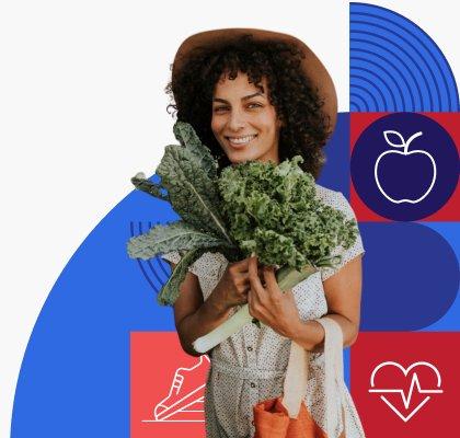 A woman with dark curly hair smiles and holds up a large bunch of kale.