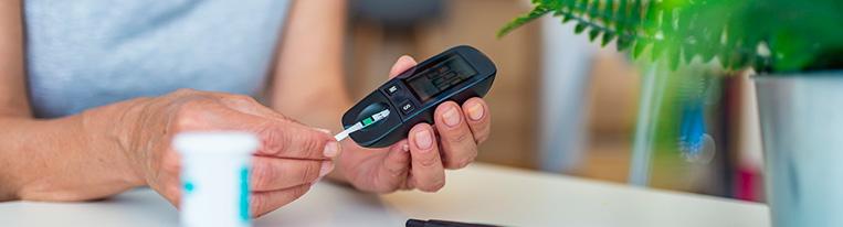 A woman checks her blood sugar with a blood glucose meter.