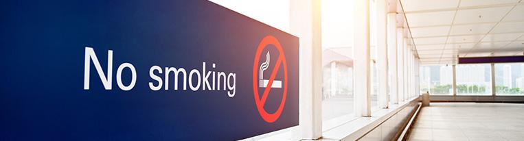 A no smoking sign hangs in a window-lined hallway.