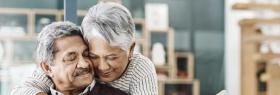 An older couple embraces at home